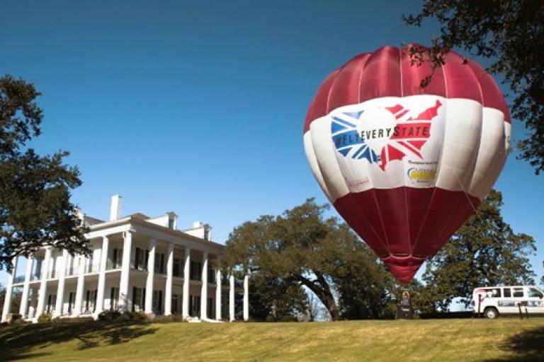 A red and white hot air balloon sits on the right side of a green field