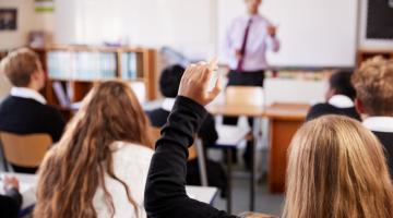 Pupil is holding hand up in a classroom